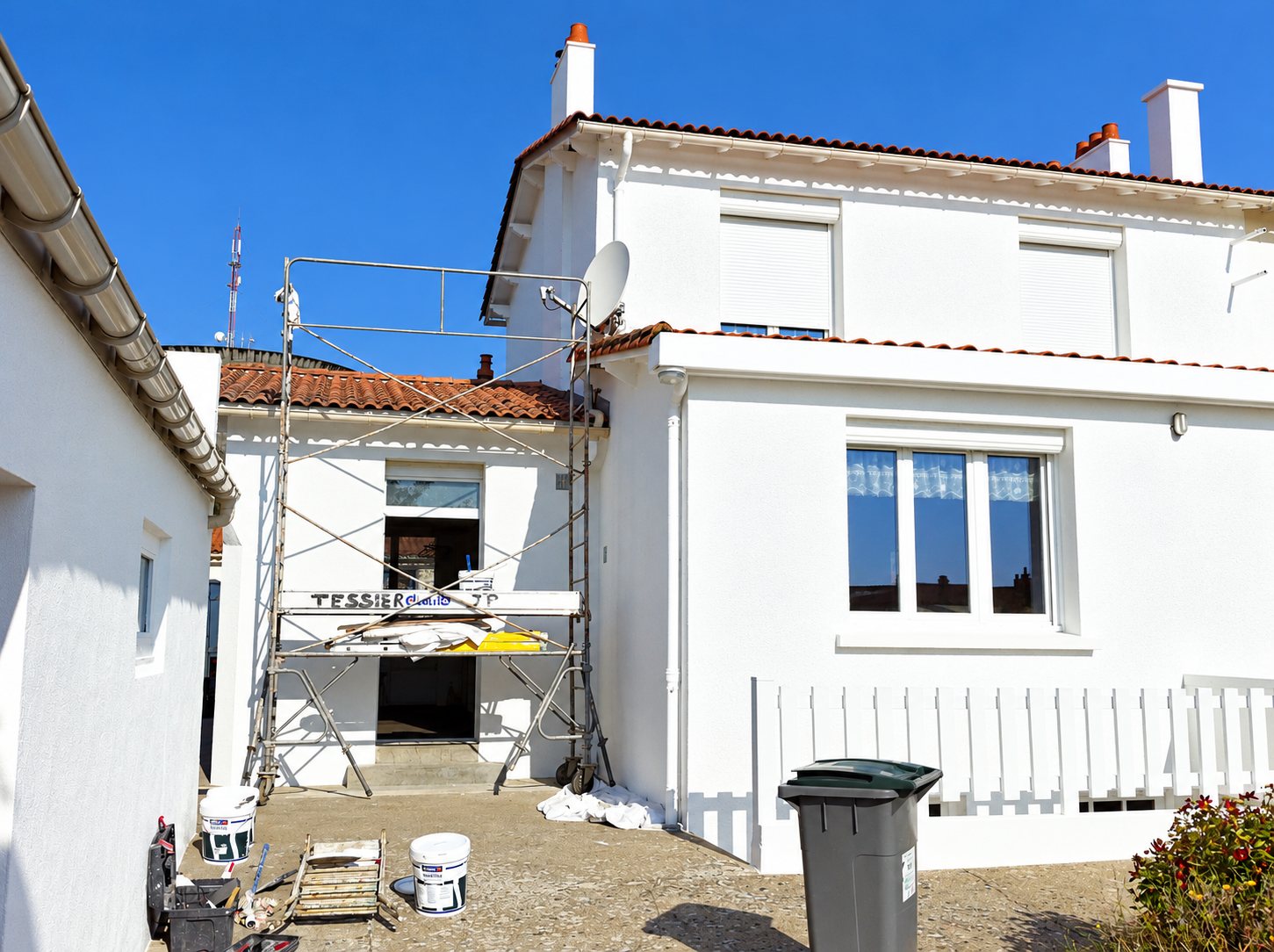 Façade de maison repeinte en blanc avec échafaudage