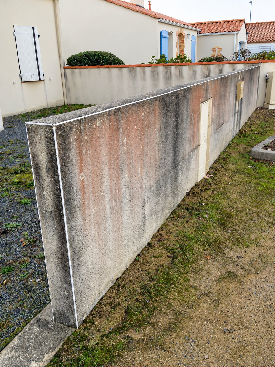 Mur de clôture en béton sali par des algues et de la mousse