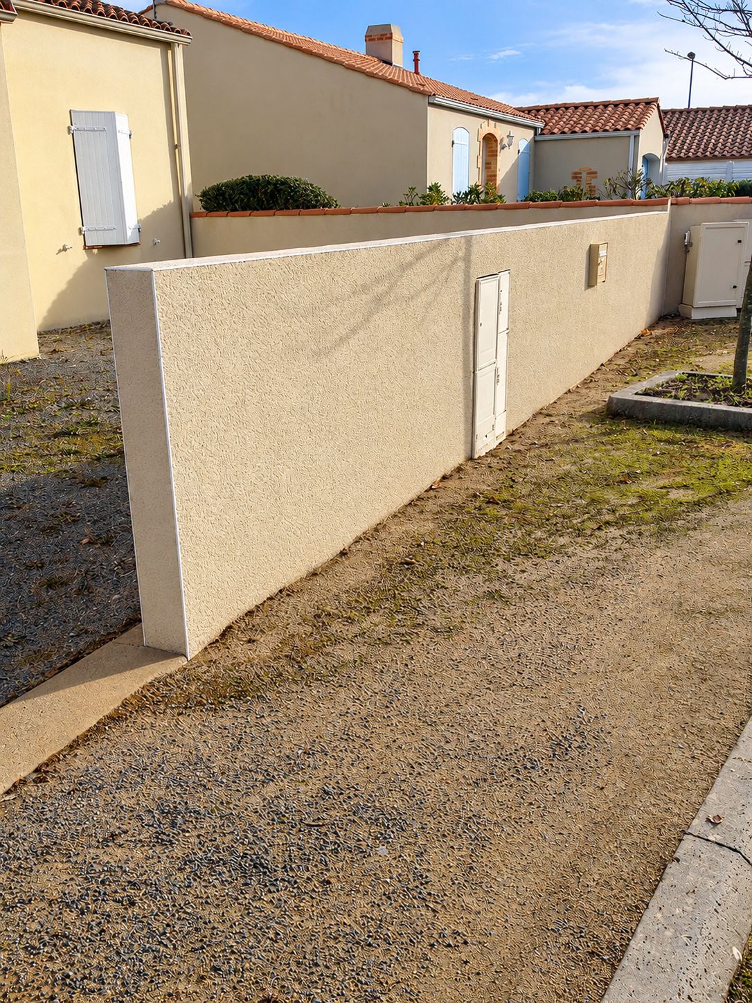 Mur de clôture en crépi beige dans un lotissement